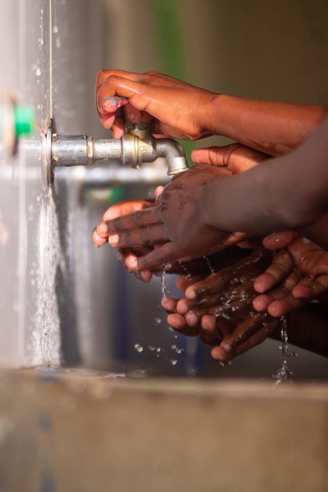 Gros plan sur des mains d'enfants capverdiens sous l'eau des robinets