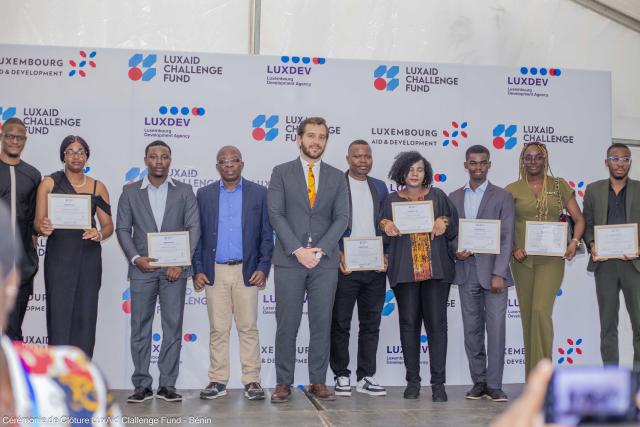 Groupe de personnes posant sur un podium, certains tenant des certificats. 