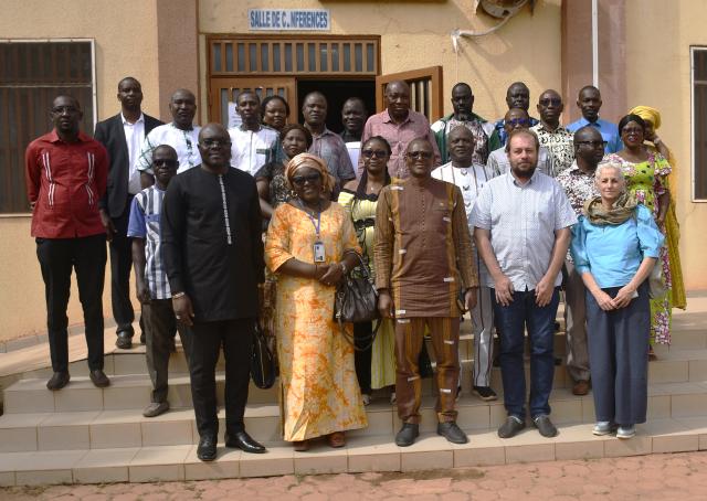 Groupe de personnes posant debout à l'entrée d'une salle de conférence