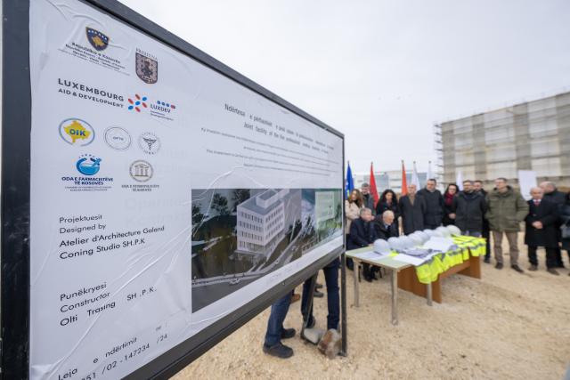 Official plaque describing details of the contract for the new building at the construction site with the ceremony in the background
