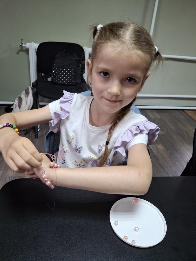 A little girl making a beaded bracelet