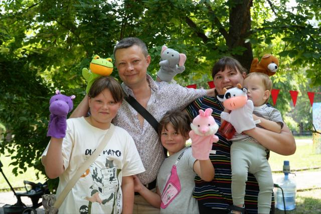 Family photo: the parents and their three children pose with puppets