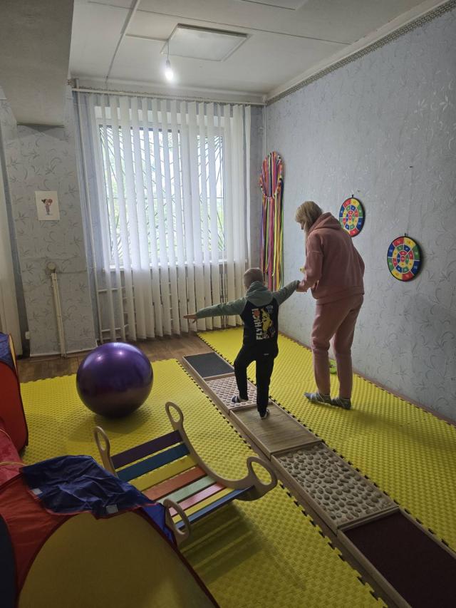 A young boy and a woman holding hands while learning to walk