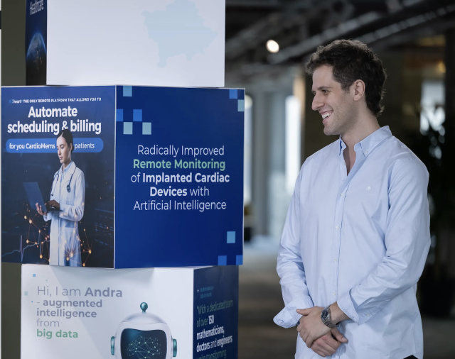 a man smiling near a pillar showing images of a project