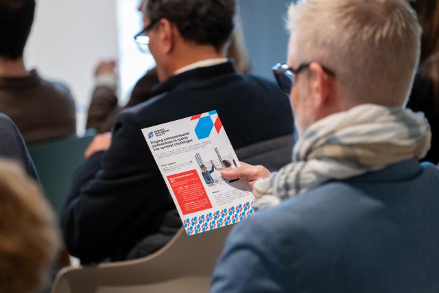 Person sitting in a conference and looking at a flyer